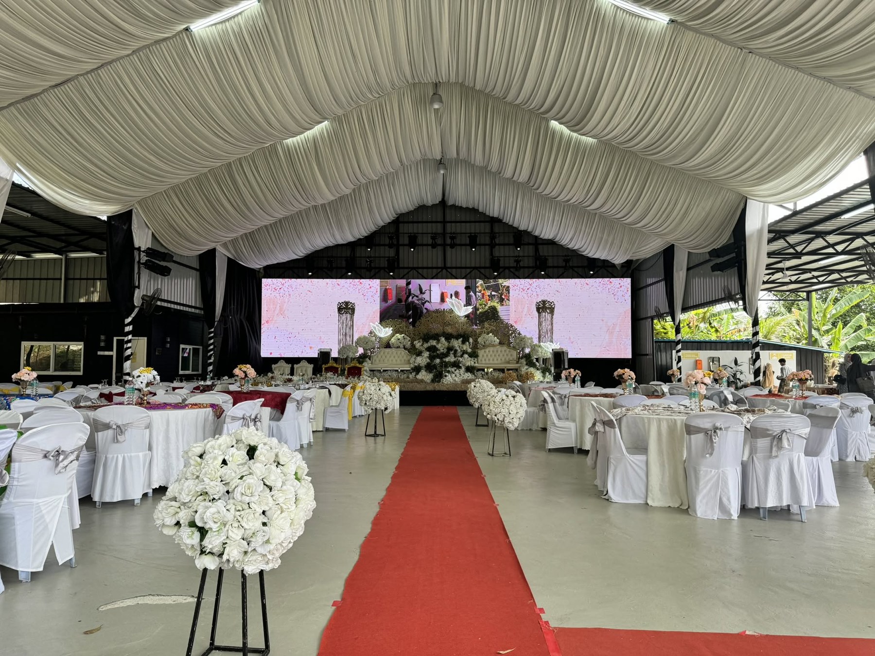 Susunan dewan majlis Qudwah dengan meja tetamu, pelamin dan laluan karpet merah